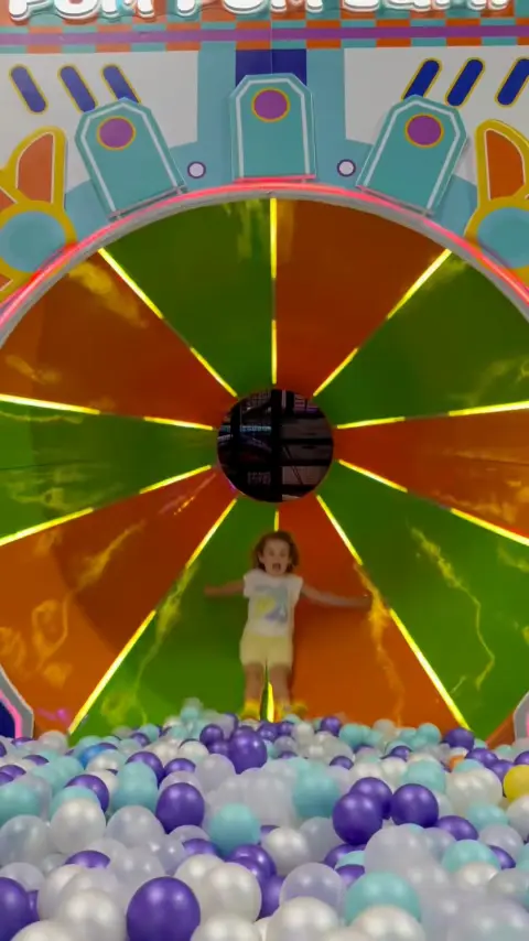 Niña en el tobogán de la piscina de bolas